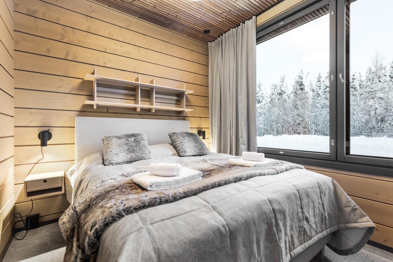 Slaapkamer met tweepersoonsbed en uitzicht op het bos