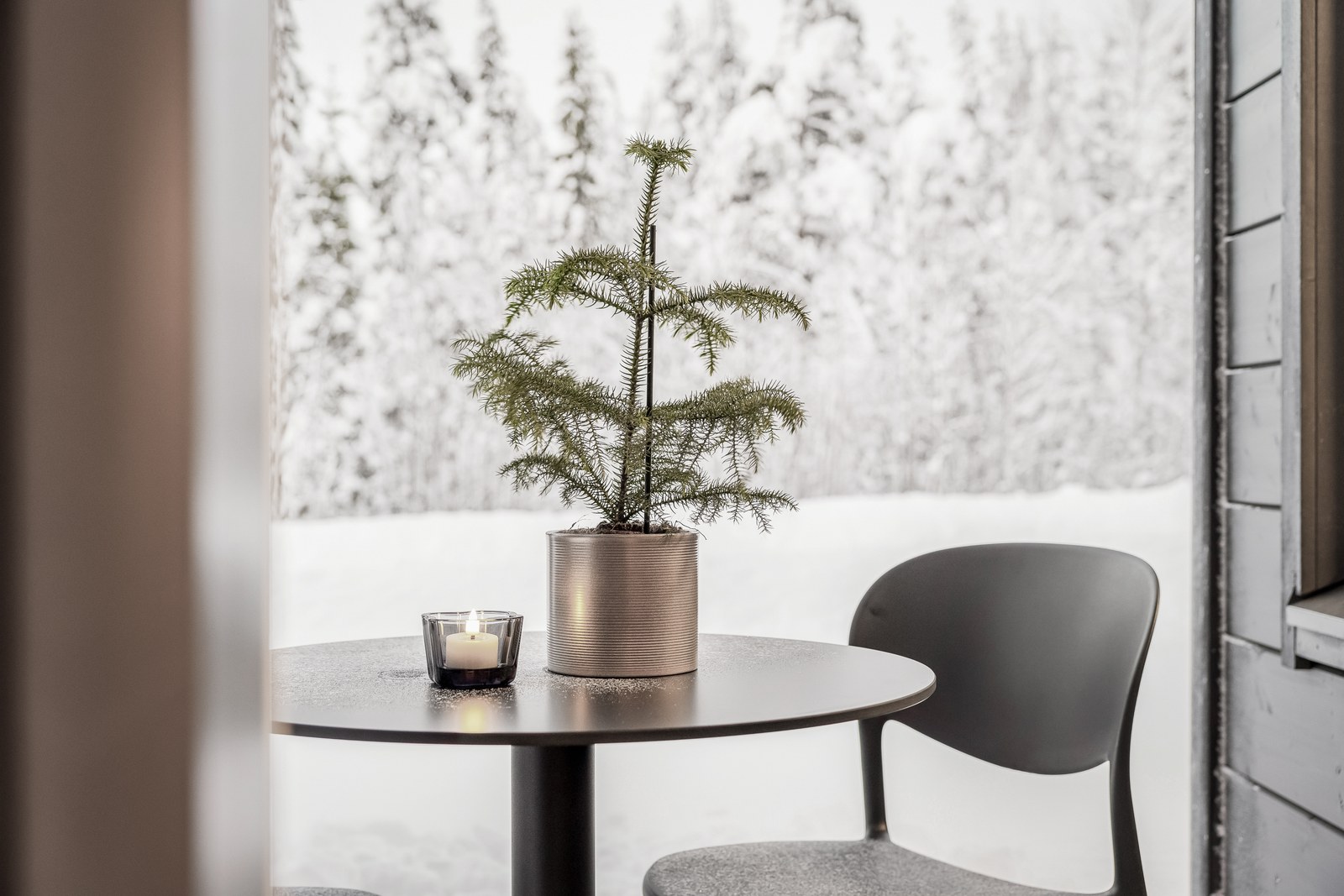 Bijzettafel met dennenboompje en zicht op de besneeuwde natuur