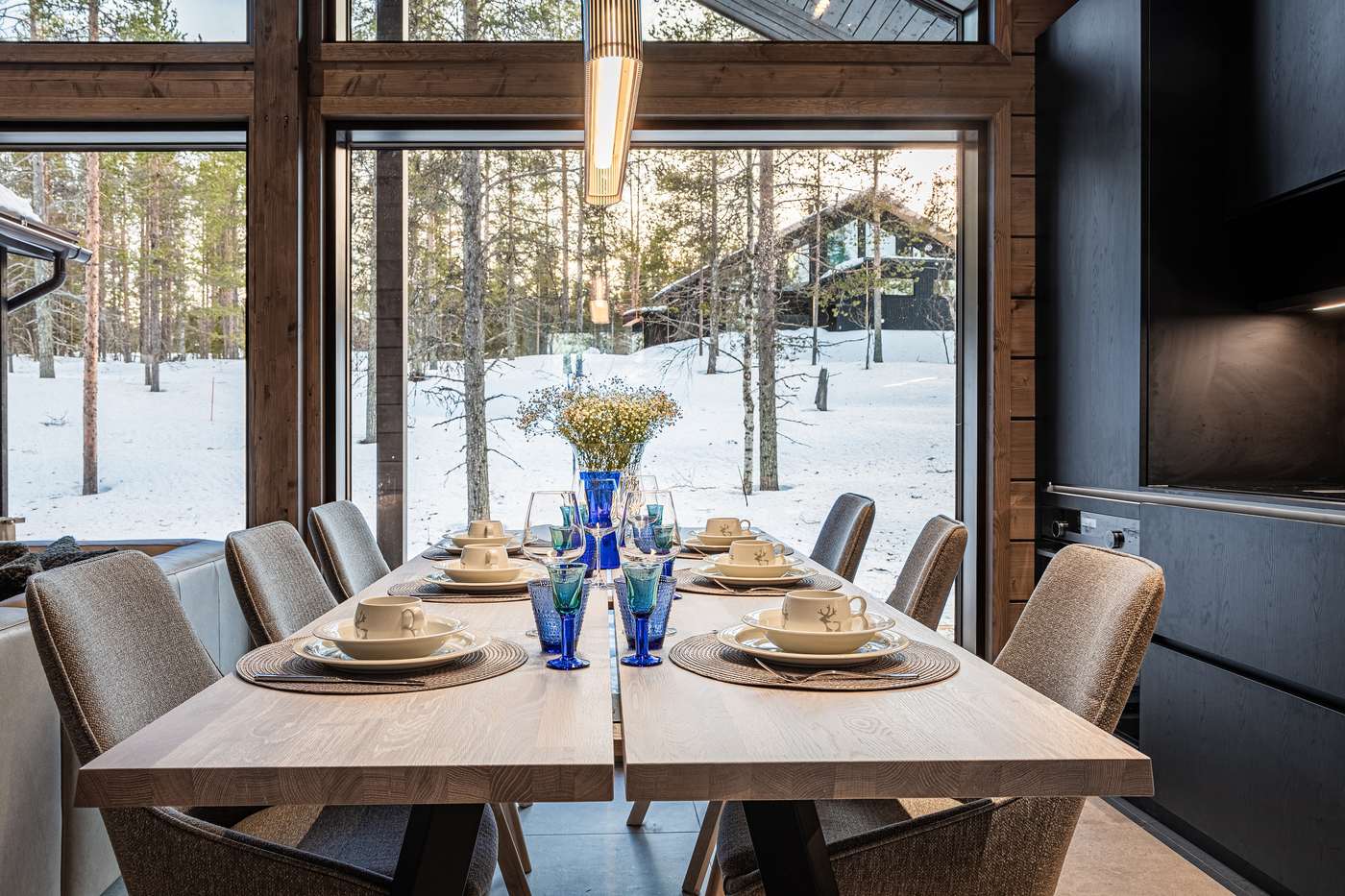 Dining table laid in front of large windows onto the forest