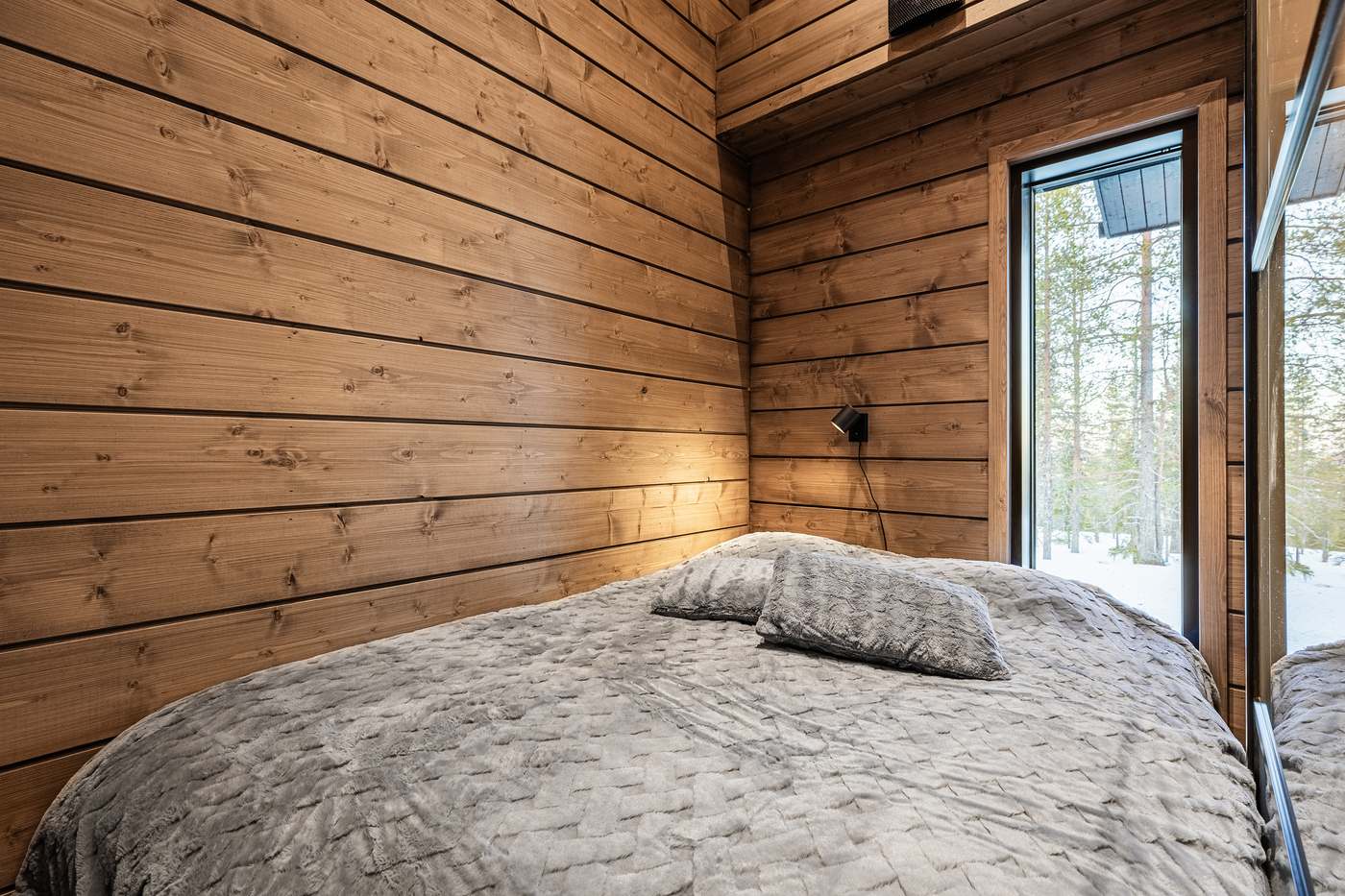 Bedroom with timber walls and a view of the forest