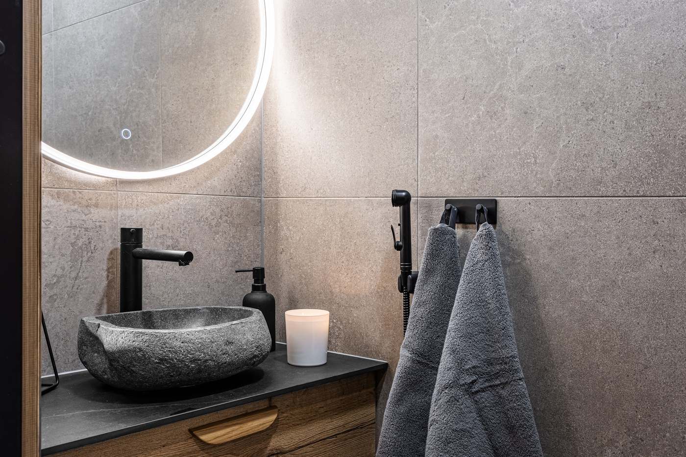 Bathroom with stone basin and illuminated round mirror